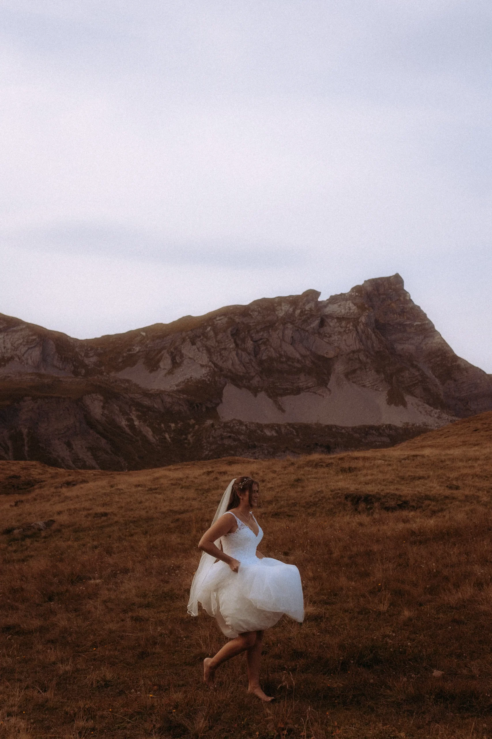 Braut barfuß in Hochzeitskleid vor Bergkulisse