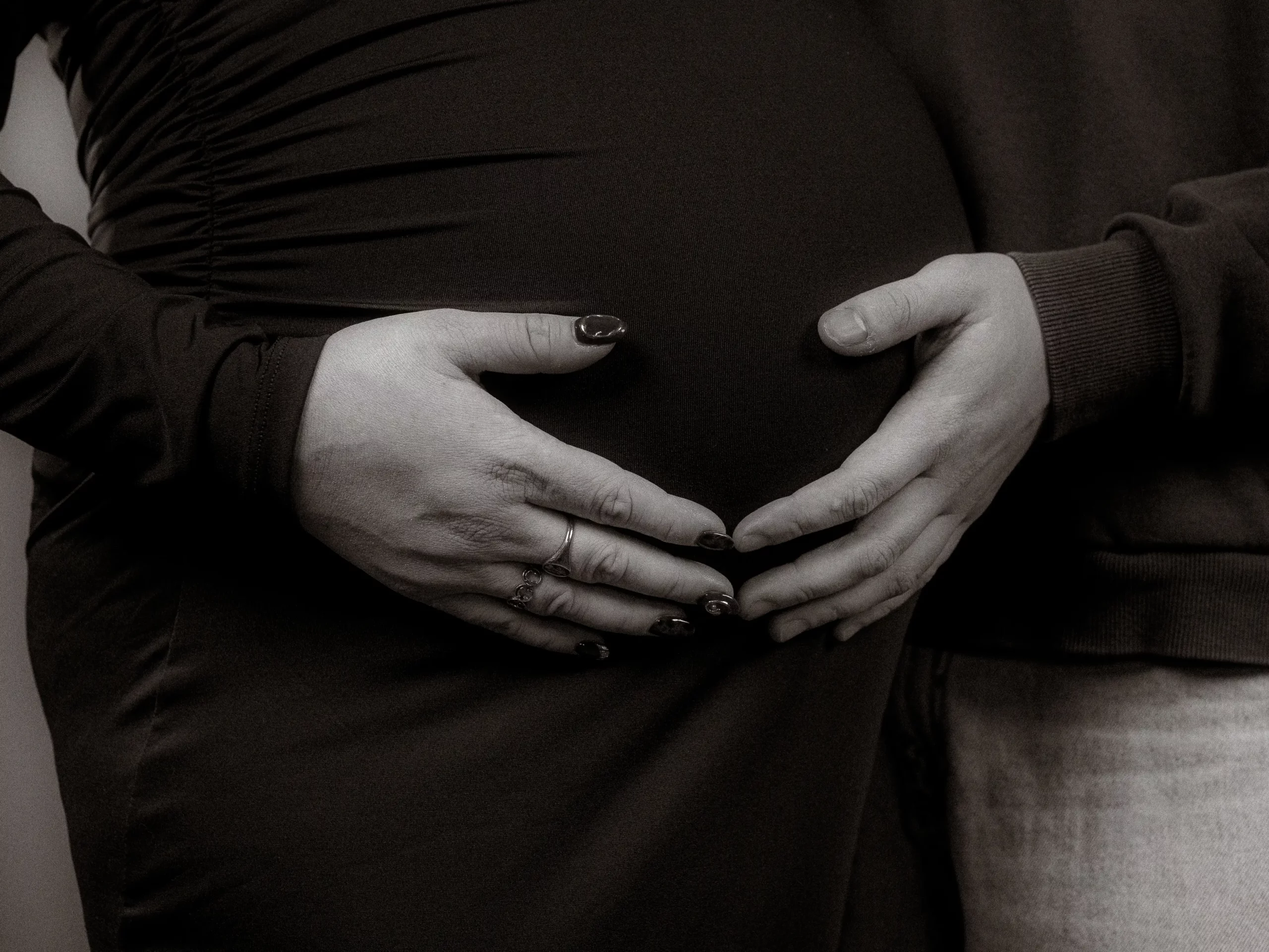 Hände formen Herz auf Babybauch