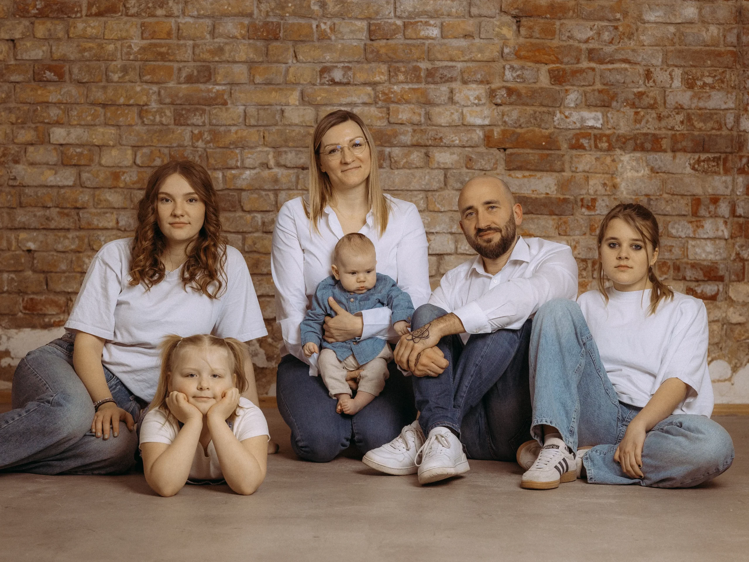 Familienfoto MV: Glückliche Familie mit drei Töchtern und Baby vor Backsteinwand. Der Fotograf aus Schwerin hat die Familie herzlich in Szene gesetzt.