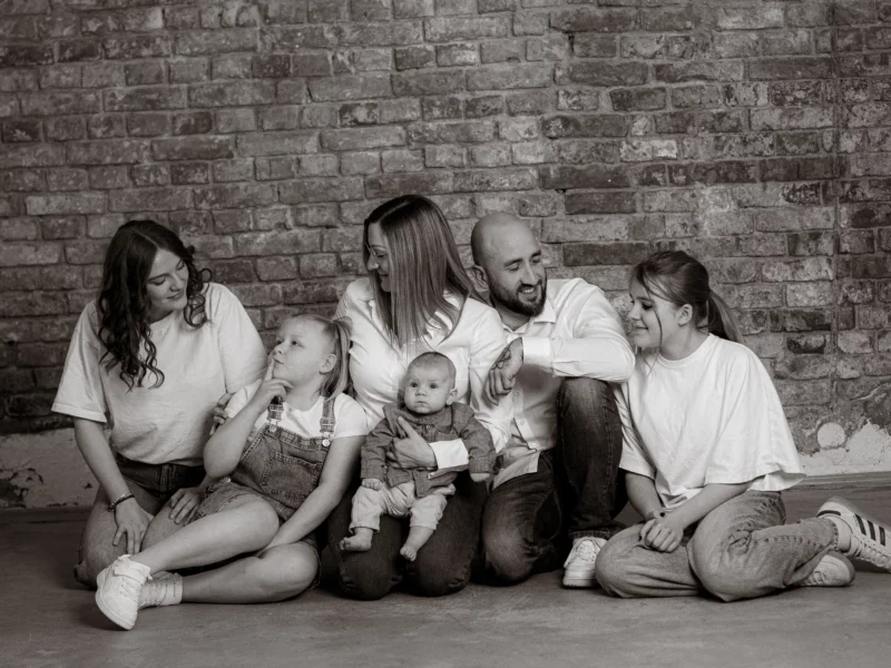 Familienfoto MV: Glückliche Familie mit drei Kindern vor einer Backsteinwand. Der Fotograf aus Schwerin hat die Familie liebevoll in Szene gesetzt.