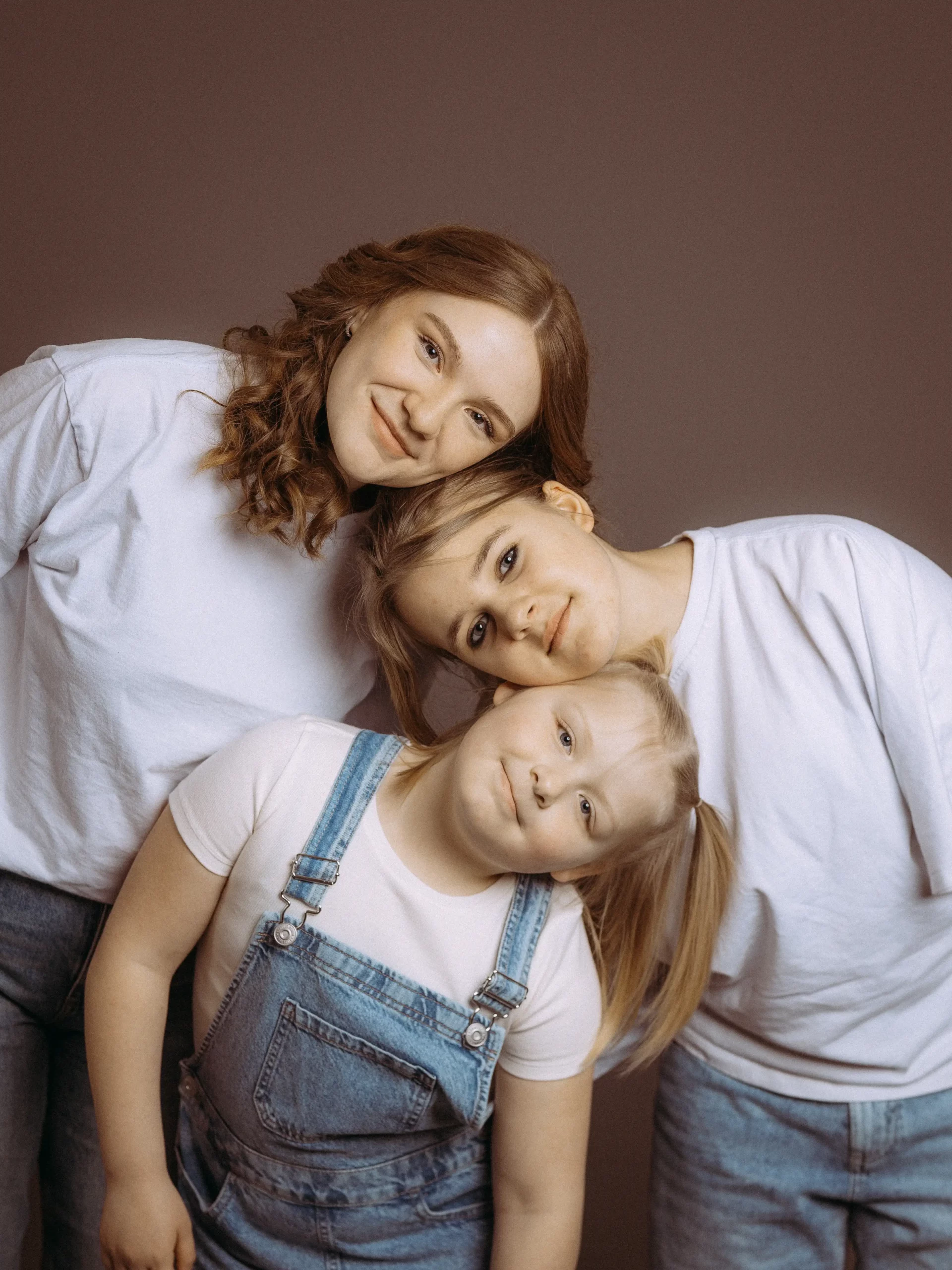 Drei Schwestern kuscheln, lächeln in die Kamera. Familienfotos MV zeigen innige Verbundenheit. Fotograf in MV fängt emotionale Momente ein.