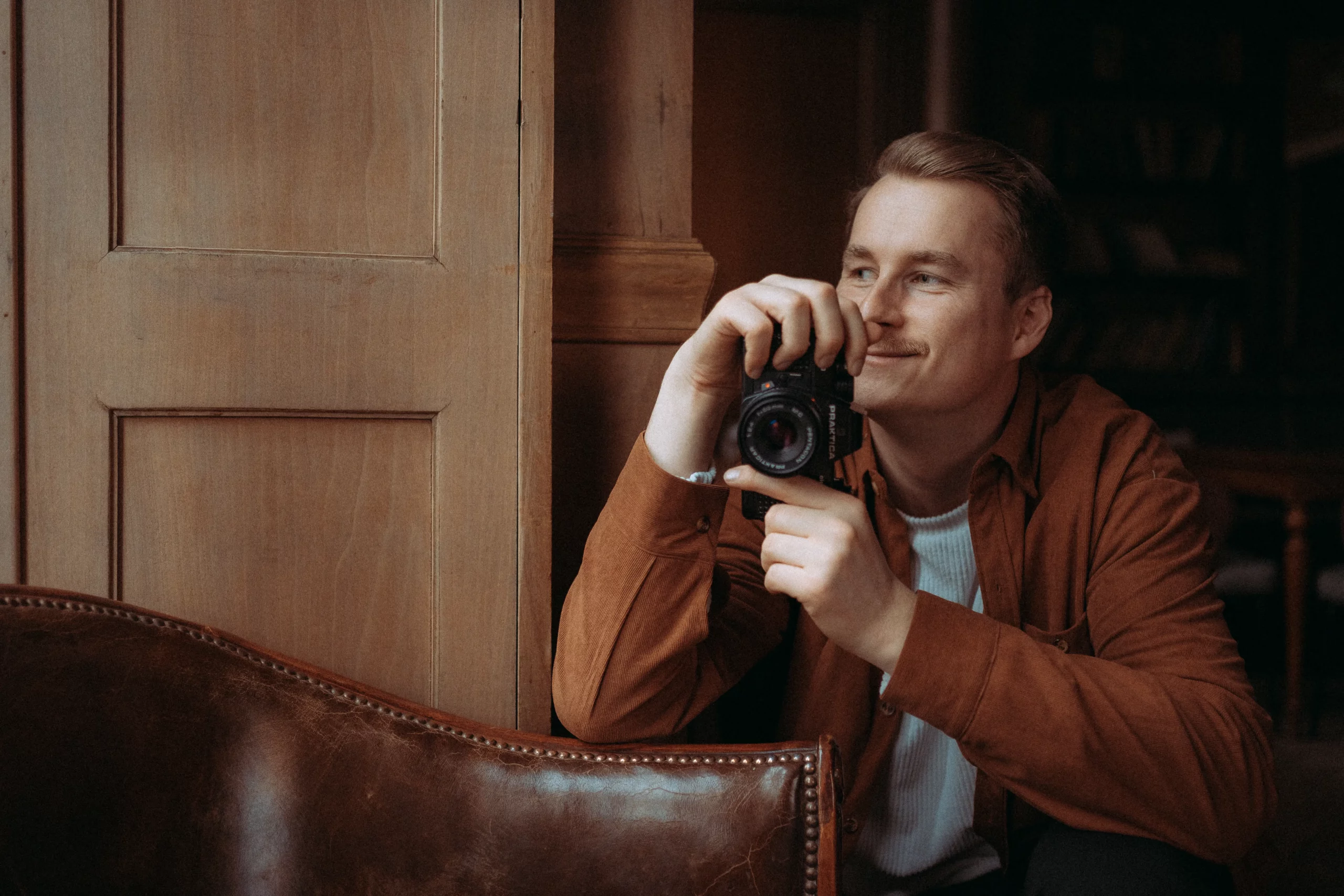 Mann mit Kamera in einem gemütlichen Raum