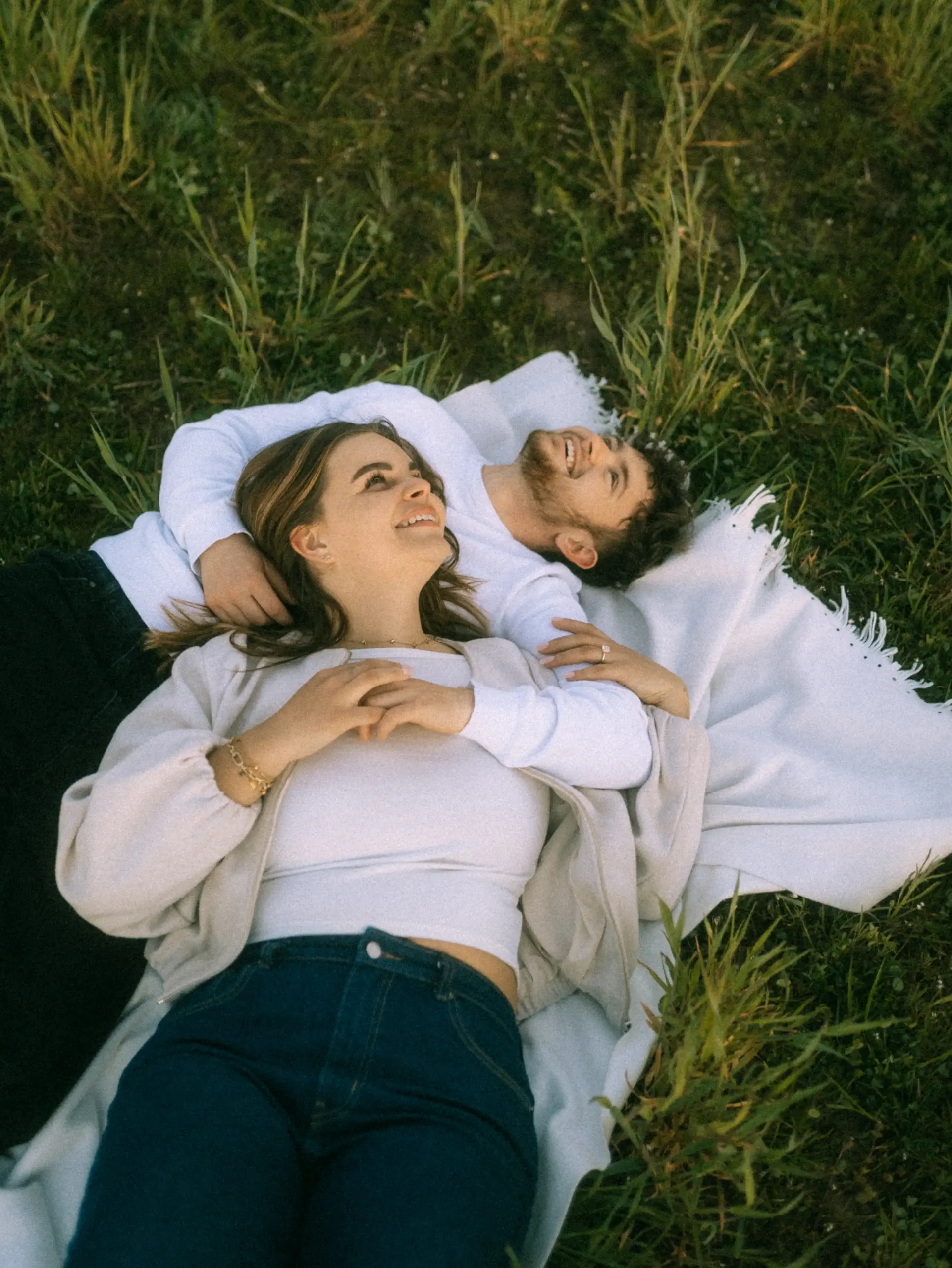 Couple holding hands and running through a grassy field at sunset.