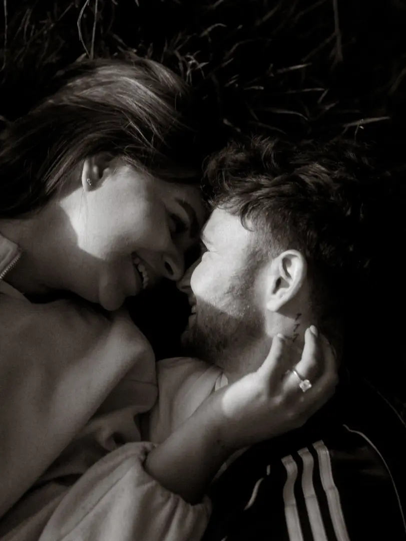 Ein verliebtes Paar in einer intimen Nahaufnahme bei einem Fotoshooting für Pärchenfotos in Schwerin. Die beiden liegen sich gegenüber, schauen sich liebevoll in die Augen und lächeln, während die Frau sanft den Hals des Mannes berührt, was eine romantische und vertraute Stimmung erzeugt.