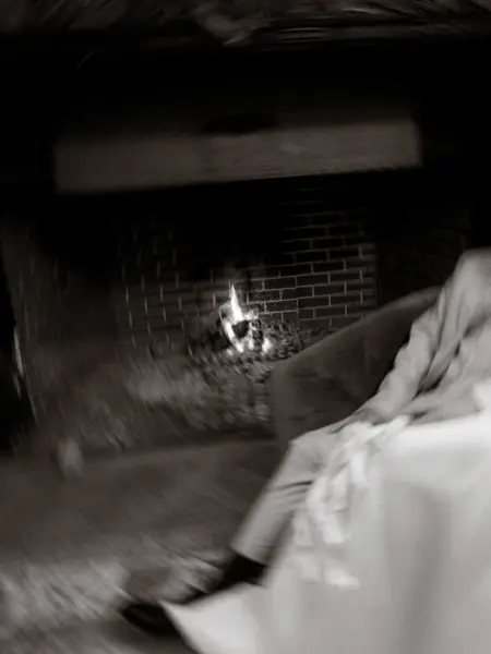 Ein Brautpaar sitzt in einer romantischen, leicht verschwommenen Aufnahme entspannt vor einem knisternden Kaminfeuer. Diese intime Szene wurde von einem Lovestory Fotograf in Schwerin und MV festgehalten, der die gemütliche Atmosphäre des Abends perfekt einfängt.