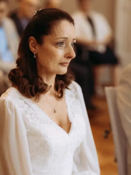 Eine emotional gerührte Braut mit dunklem Haar und elegantem weißem Spitzenkleid blickt bei einer Hochzeitszeremonie nachdenklich zur Seite. Die Aufnahme fängt einen intimen Moment voller Gefühl ein, festgehalten durch einen Hochzeitsfotograf in Schwerin und MV.