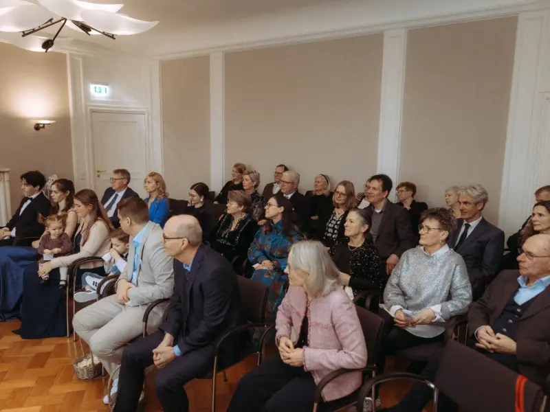 Eine festlich gekleidete Hochzeitsgesellschaft sitzt in einem hellen, eleganten Saal und verfolgt aufmerksam die Zeremonie. Als Hochzeitsfotograf in Schwerin und MV halte ich diesen emotionalen Moment fest, in dem Gäste in festlicher Kleidung gespannt in Richtung des Brautpaares blicken.