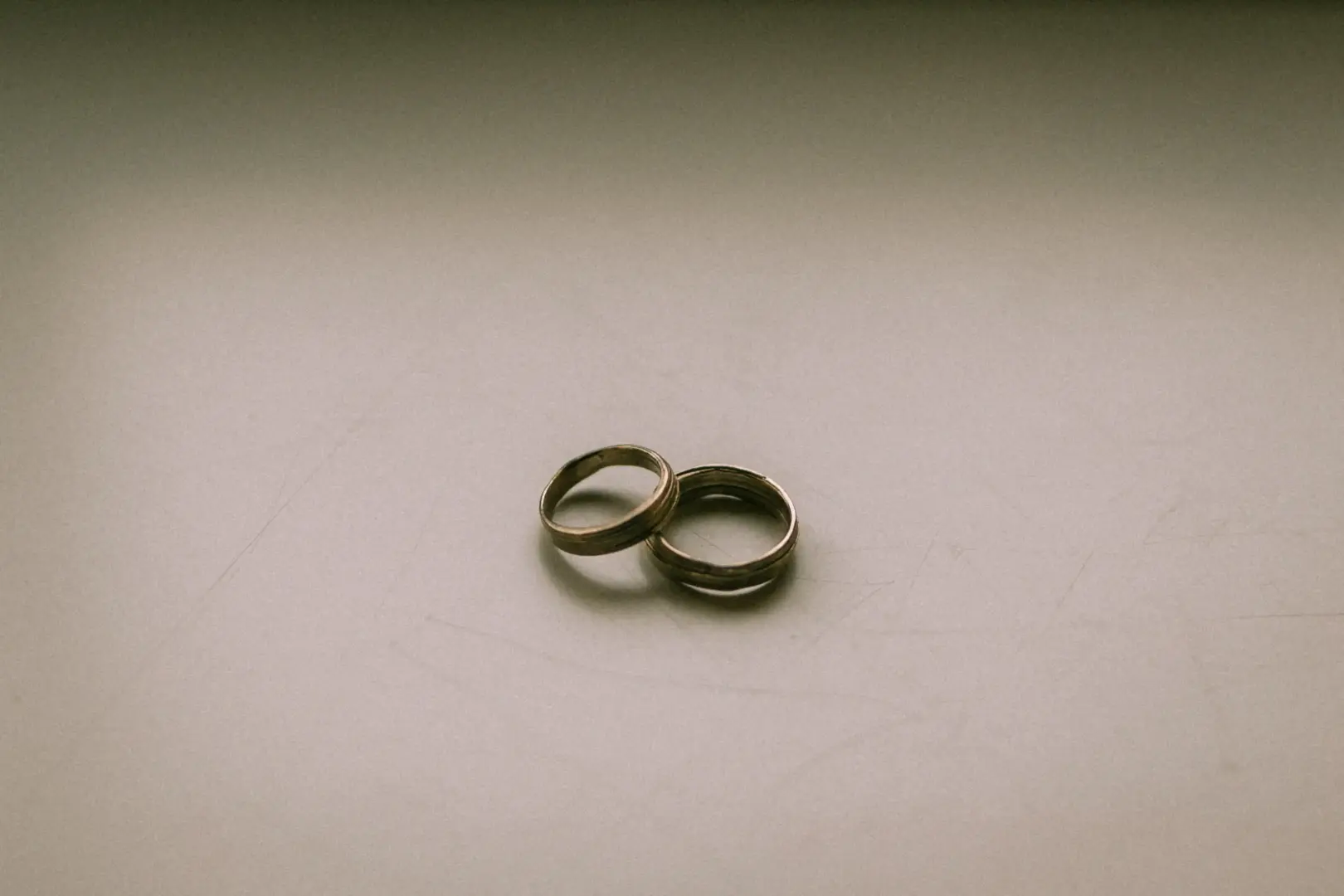 Zwei goldene Eheringe liegen leicht ineinander verschlungen auf einer schlichten, hellen Oberfläche. Die minimalistische Aufnahme fängt das Symbol der Verbundenheit ein – eine perfekte Inspiration für Paare, die einen Hochzeitsfotograf in Schwerin und MV suchen.