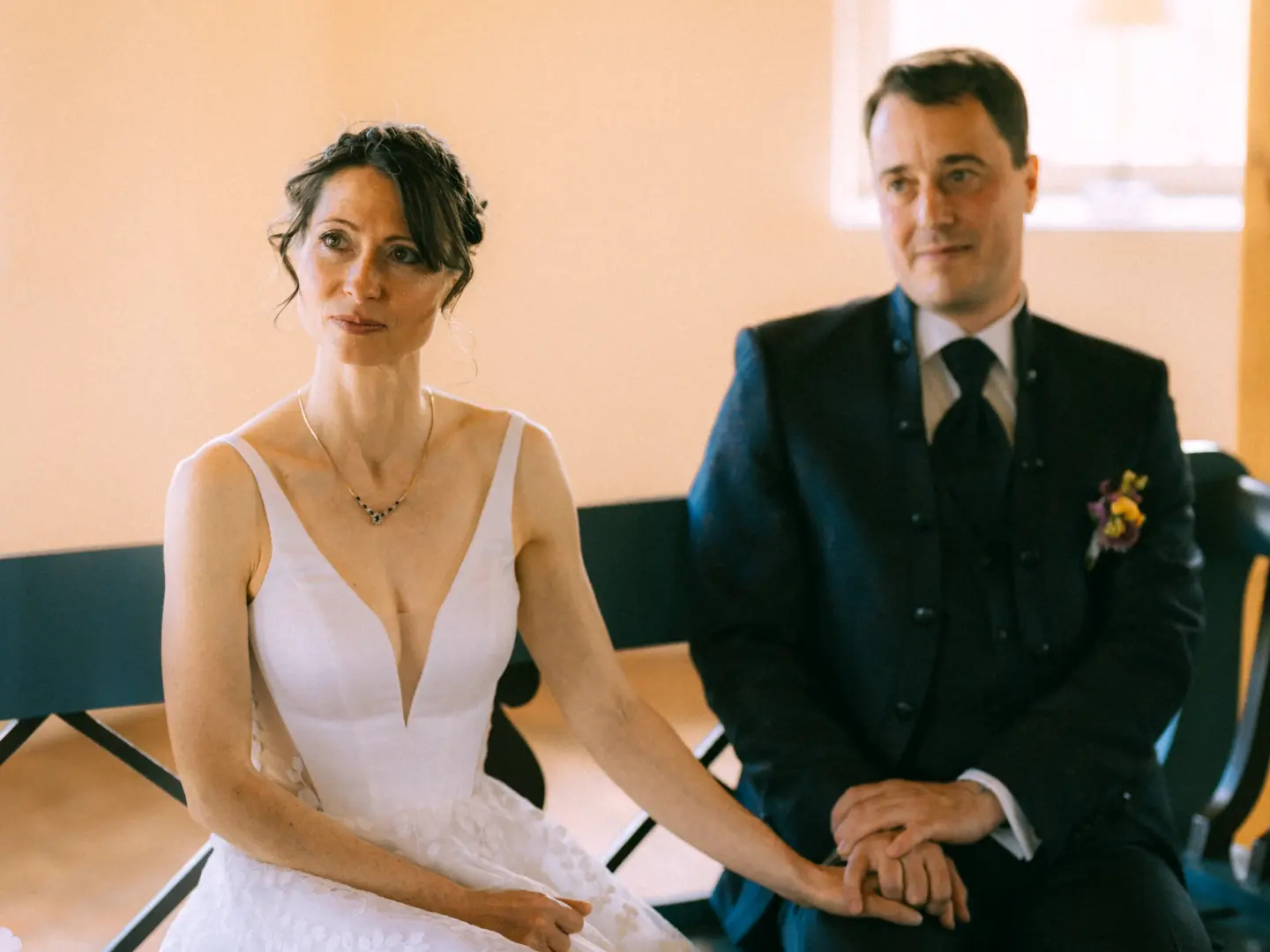 Eine Braut im eleganten weißen Kleid und ein Bräutigam im dunklen Anzug halten sich während der Zeremonie liebevoll an den Händen. Die emotionale Aufnahme wurde von einem Hochzeitsfotograf in Schwerin und MV festgehalten.