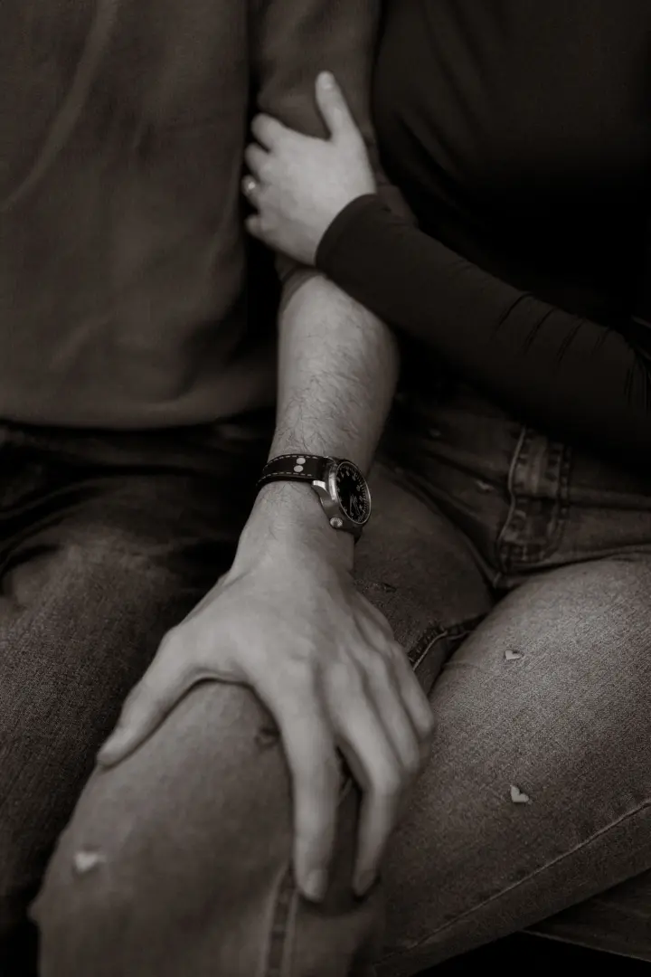 Nahaufnahme eines Paares bei einem Fotoshooting: Eine Frau hält sich zärtlich am Arm ihres Partners fest, der eine klassische Armbanduhr trägt. Die intime Stimmung unterstreicht die Verbundenheit der beiden bei einem professionellen Shooting für Pärchenfotos Schwerin.