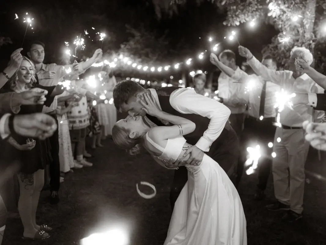 Ein frisch vermähltes Brautpaar küsst sich innig bei einem romantischen Funkenregen-Spalier ihrer Hochzeitsgäste in der Nacht. Das stimmungsvolle Foto fängt diesen besonderen Moment als Hochzeitsfotograf in Schwerin und MV perfekt ein.